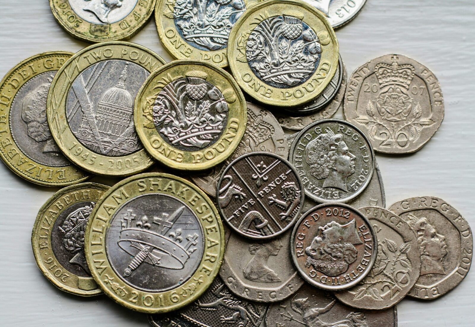 A stack of British coins arranged on a wooden table, via Unsplash (free)